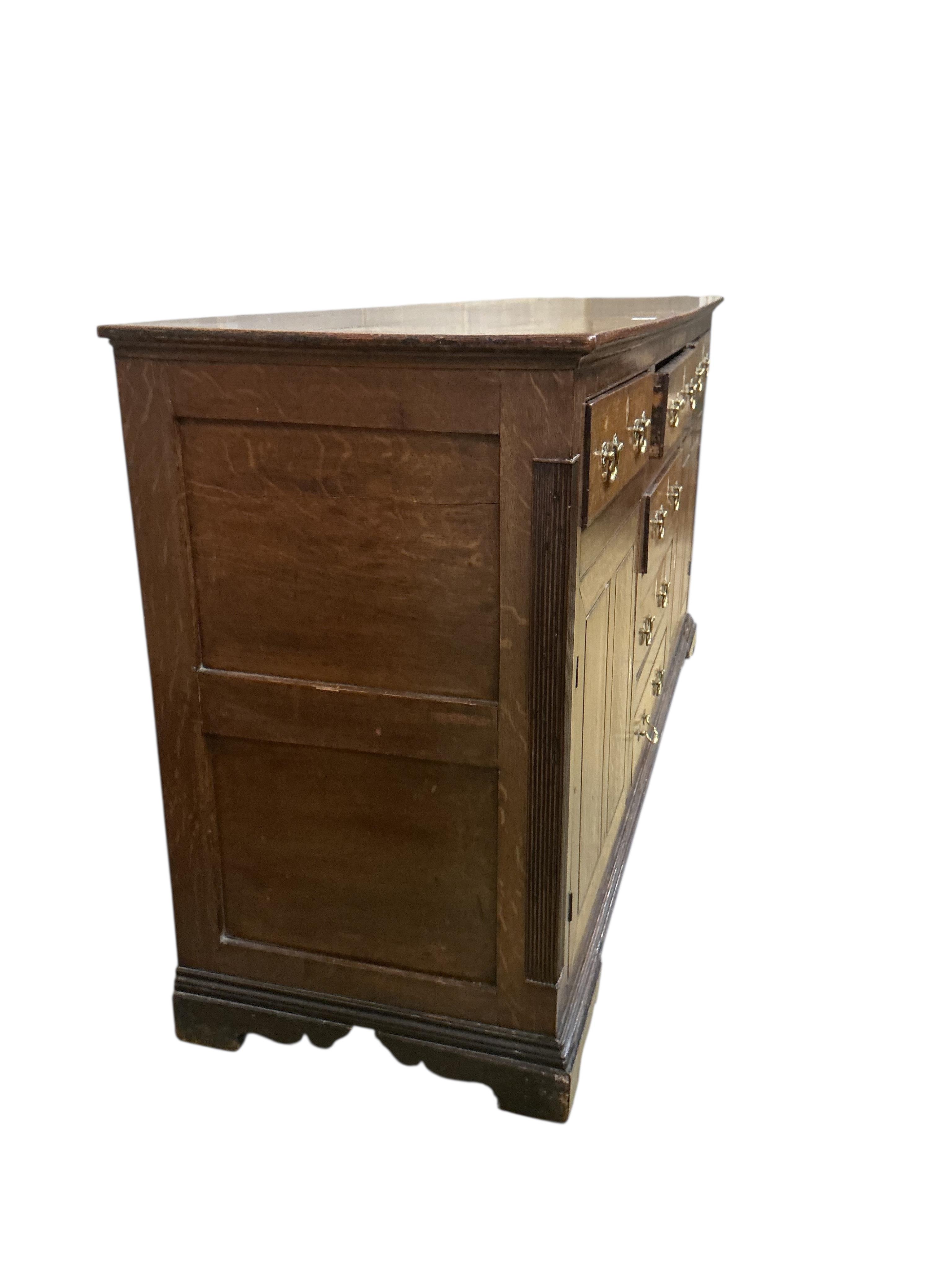 A George III oak low dresser base, later replacement handles, width 178cm, depth 54cm, height 91cm